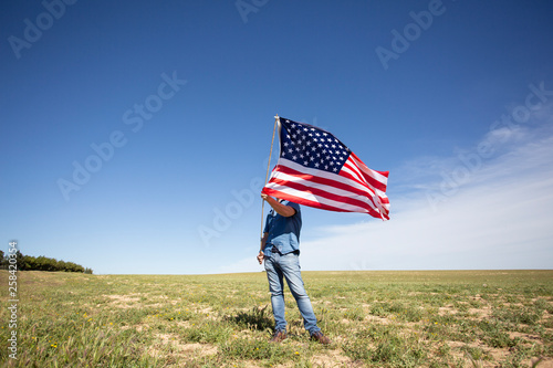 Man holding American flag on field in remote landscape