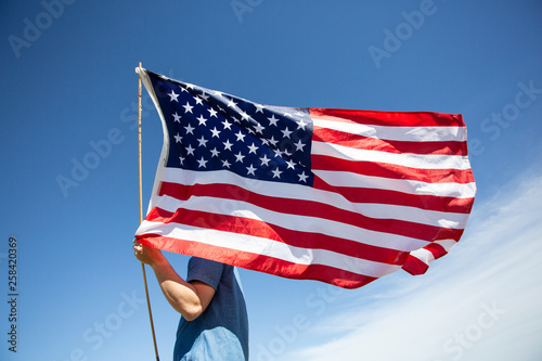 Man holding American flag under blue sky