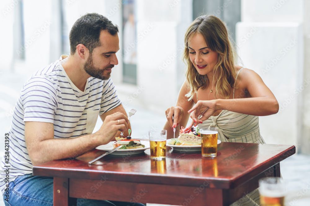 Couple eating and drinking beer in a restaurant on the street
