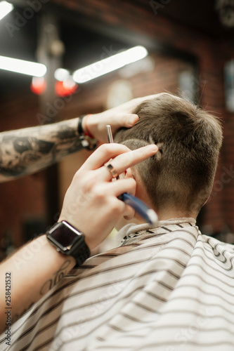 man being trimmed with electric clipper machine in barbershop.Male beauty treatment concept. Young guy getting new haircut in barber salon