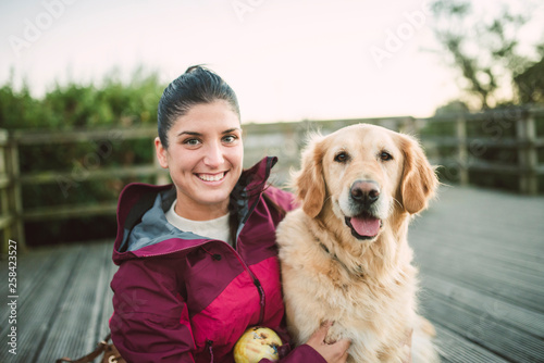 Portrait of a happy young woman with her Golden retriever dog outdoors