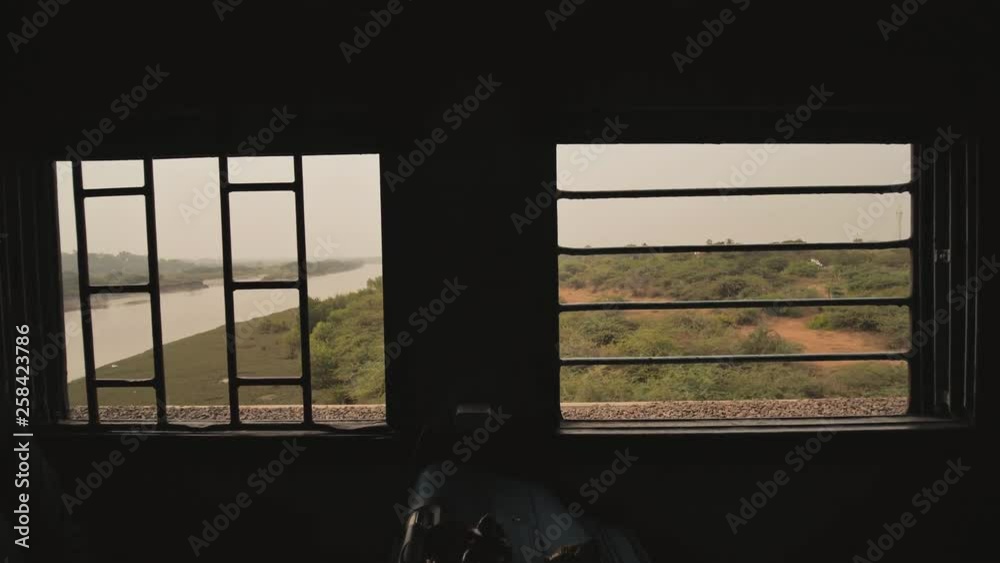 Grid windows of a traditional Indian train in motion.