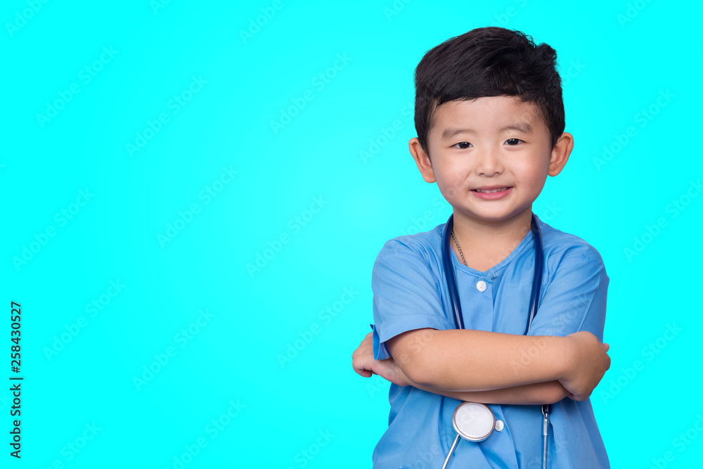 Smiling Asian kid in blue medical uniform holding stethoscope looking at camera on blue green background with copy space, healthy concept. Smiling Asian kid in blue medical uniform holding stethoscope looking at camera on blue green background with copy space, healthy concept.