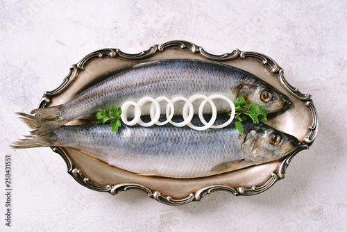 alted herring in a nickel silver platter on a light background. Top view. Copy space.  photo