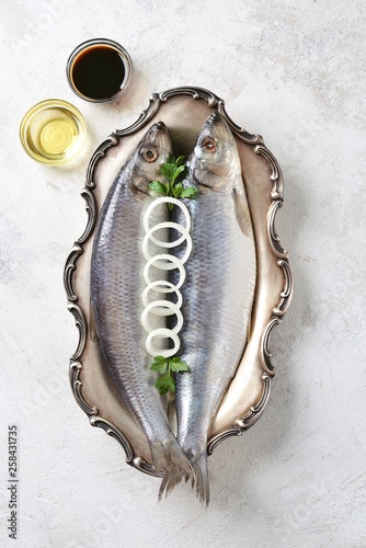 alted herring in a nickel silver platter on a light background. Top view. Copy space.  photo