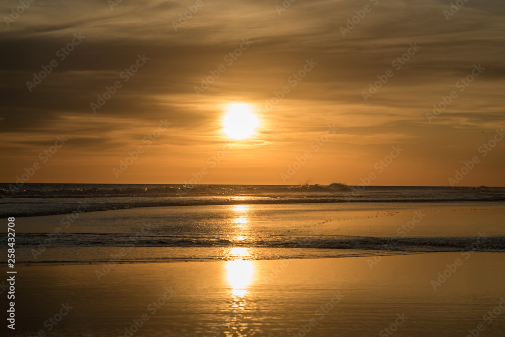 Sunset over the sea, sun reflected in the water, orange sunset, gentle waves and the brightness of the sun
