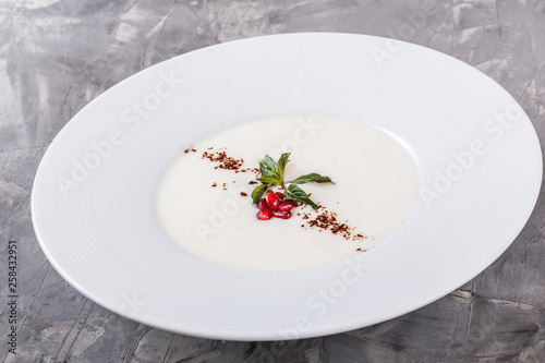 Semolina porridge with grated chocolate and pomegranate in plate over grey background. Healthy breakfast ingredients. Clean eating, vegan food concept