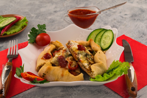 Pizza with mushrooms and spicy tomato sauce. Chopped fresh vegetables. Parsley, lettuce and dill leaves. Tasty and fast food.