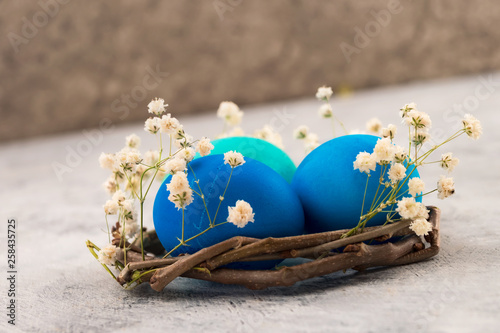 Chicken eggs for Easter in a nest of branches with white flowers. Easter decoration on a light background. Close-up.