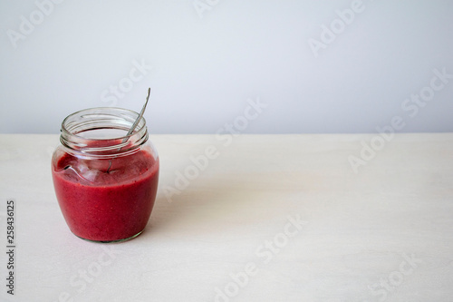 Glass jar with red jam on the table