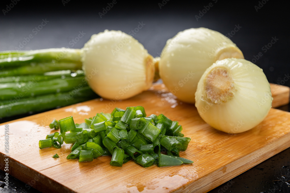 Fresh wet young onion on the kitchen table. Sliced chives on a kitchen board. Fresh wet young onion on the kitchen table. Sliced chives on a kitchen board.