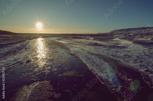 Sun setting over frozen river in Iceland highlands on a winter day