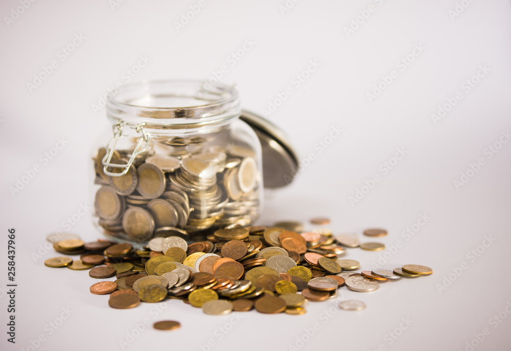 EURO coins in glass jar with colorful coins outside on clear background EURO coins in glass jar with colorful coins outside on clear background