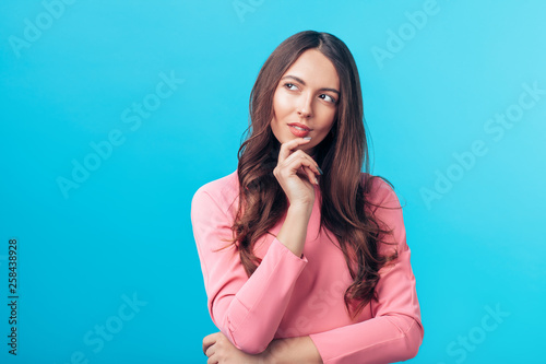 Obraz na plátne Portrait of thoughtful wondering woman looking sideways isolated over blue backg