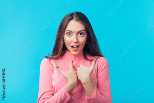 Surprised beautiful woman points at oneself with both hands