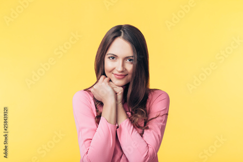 Beautiful smiling woman posing over yellow background