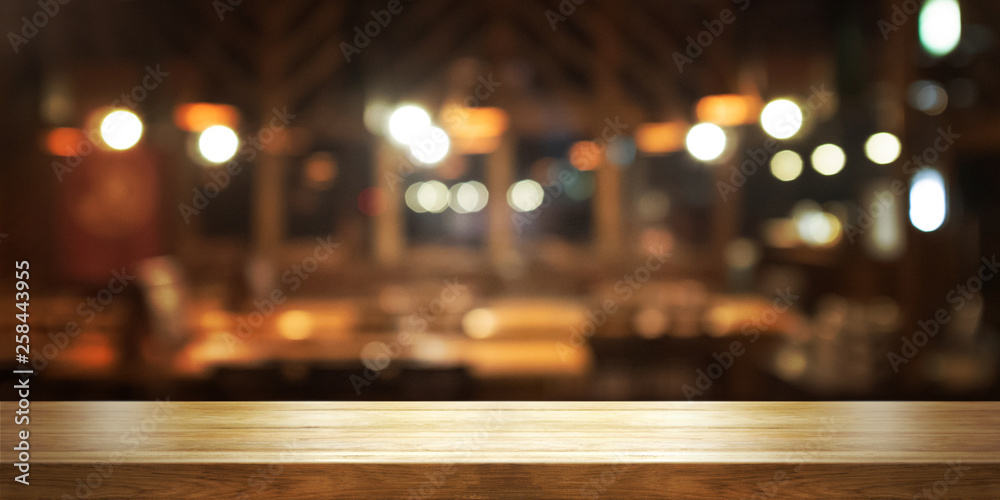 Empty wooden table top with blur coffee shop or restaurant interior background, Panoramic banner. Abstract background can be used for display.