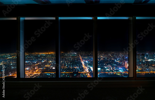 Aerial view of the Osaka skyline at night through a skyscraper window