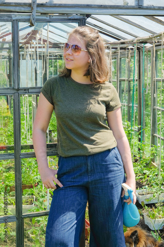 Girl watering tomato seedlings from watering can. The gardener sprays the plants from pests and bugs.