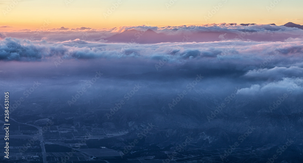 Stunning view of Earth and Heaven: night city beneath blue clouds and golden and pink sky