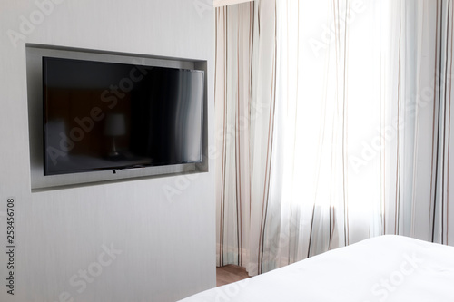 television hanging on a wall by the window inside bedroom