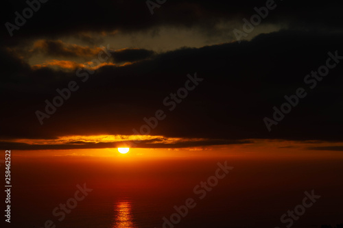 The rising over the ocean with dramatic clouds as viewed from an elevated vantage point.