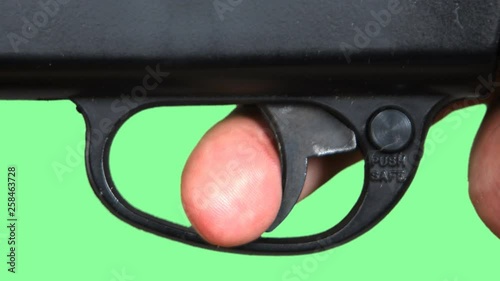 Pulling a trigger of a gun against a green screen. 
