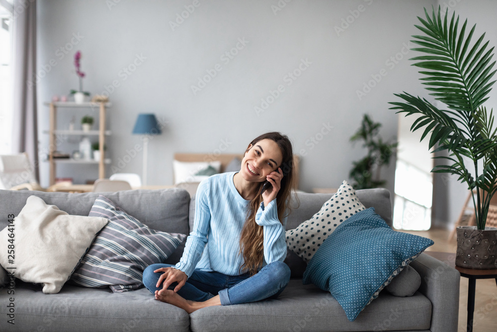 Attractive smiling woman talking on the phone at home. - obrazy, fototapety, plakaty 