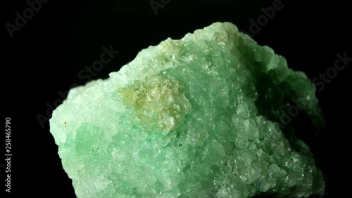 Large rock of green halite, rock salt, rotating on black background.
