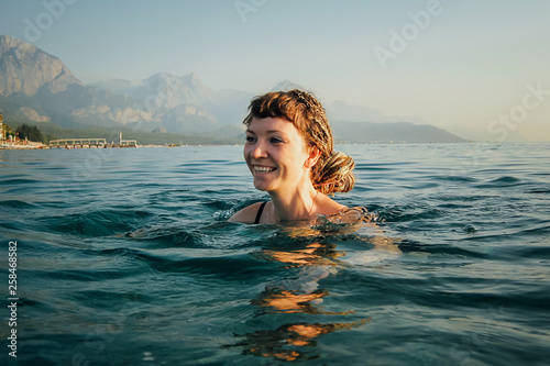 The girl swims in the blue sea. only her head is visible