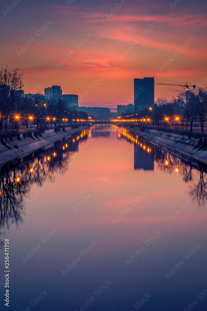 Vibrant cityscape shot early morning before sunrise in Bucharest with a river in the foreground