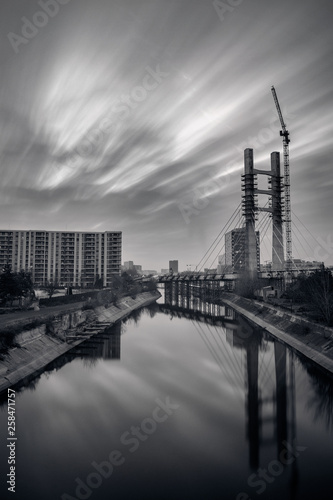 Black and white cityscape with a bridge in construction near a crane and high buildings in Bucharest