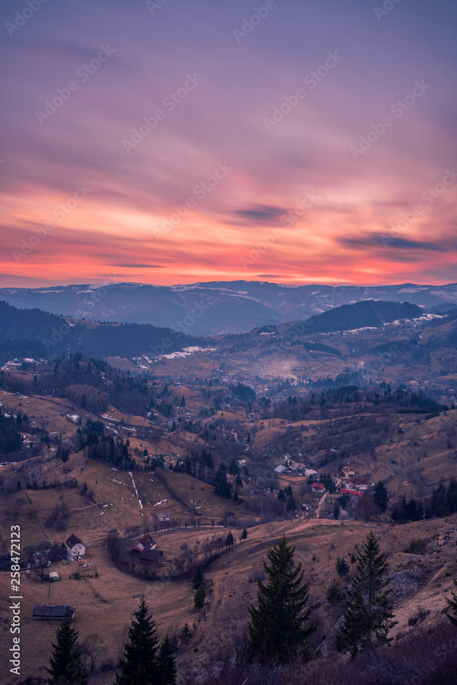 Small village placed in a valley between mountains seen from above at sunset shot in Romania with a long exposure