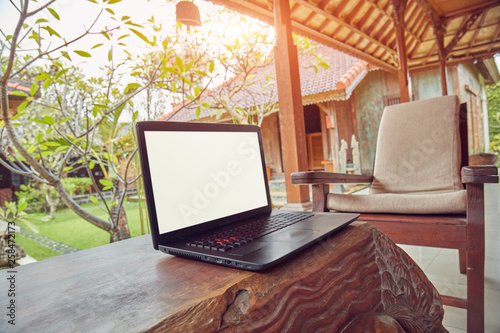 Laptop on a home porch / patio with view to a garden.
