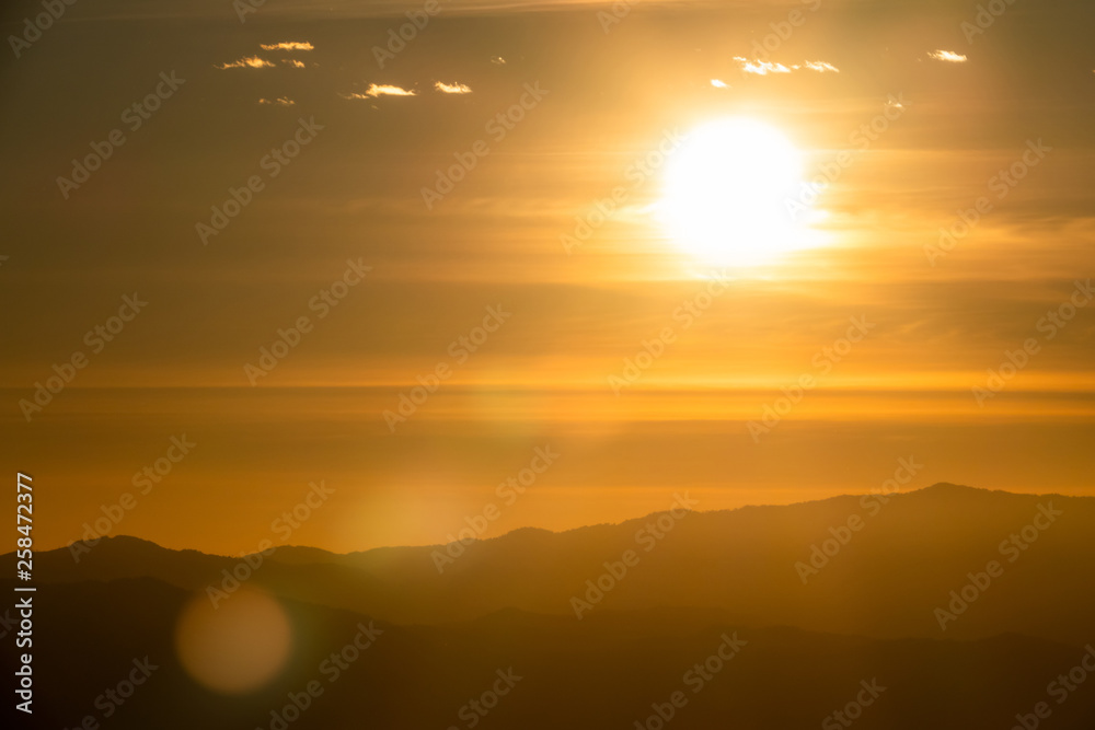 Landscape view of sunrise over the mountains and morning fog. The sun shining golden light with bokeh flare to forest, mountain. Northern in Thailand.