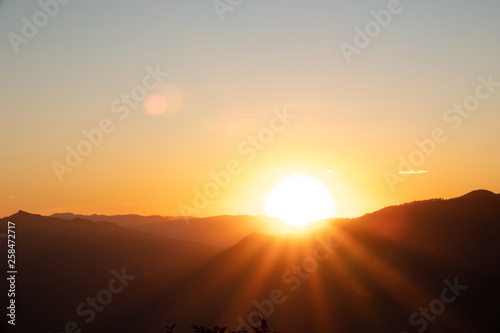 Landscape view of sunrise over the mountains and morning fog. The sun shining golden light with bokeh flare to forest  mountain.
