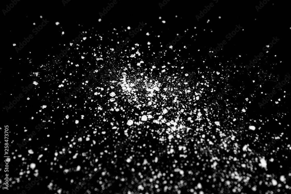 white crystalline powder on a black background. sugar dust white crystalline powder on a black background. sugar dust