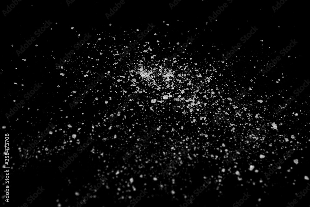 white crystalline powder on a black background. sugar dust white crystalline powder on a black background. sugar dust