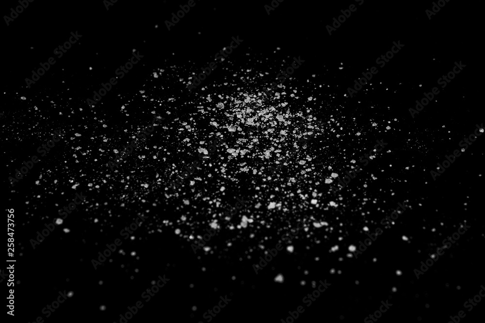 white crystalline powder on a black background. sugar dust white crystalline powder on a black background. sugar dust