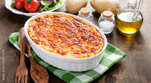 Potato casserole with meat on  wooden table.