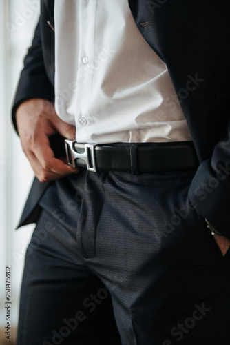 A man in a black suit and white shirt poses indoors for advertising men's clothing. Shooting for men's clothing store