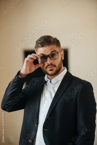 A man in a black suit and white shirt poses indoors for advertising men's clothing. Shooting for men's clothing store
