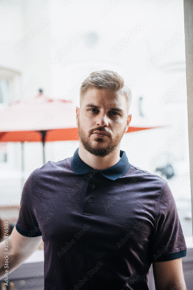 A man in a purple polo and posing for advertising men's clothing. Shooting for men's clothing store A man in a purple polo and posing for advertising men's clothing. Shooting for men's clothing store