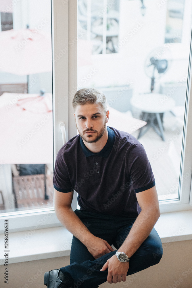Fototapeta premium A man in a purple polo and posing for advertising men's clothing. Shooting for men's clothing store