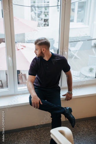 A man in a purple polo and posing for advertising men's clothing. Shooting for men's clothing store