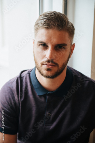 A man in a purple polo and posing for advertising men's clothing. Shooting for men's clothing store