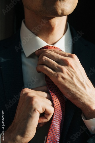 Male model in black suit and red tie poses for men's clothing advertising. Shooting for men's clothing store