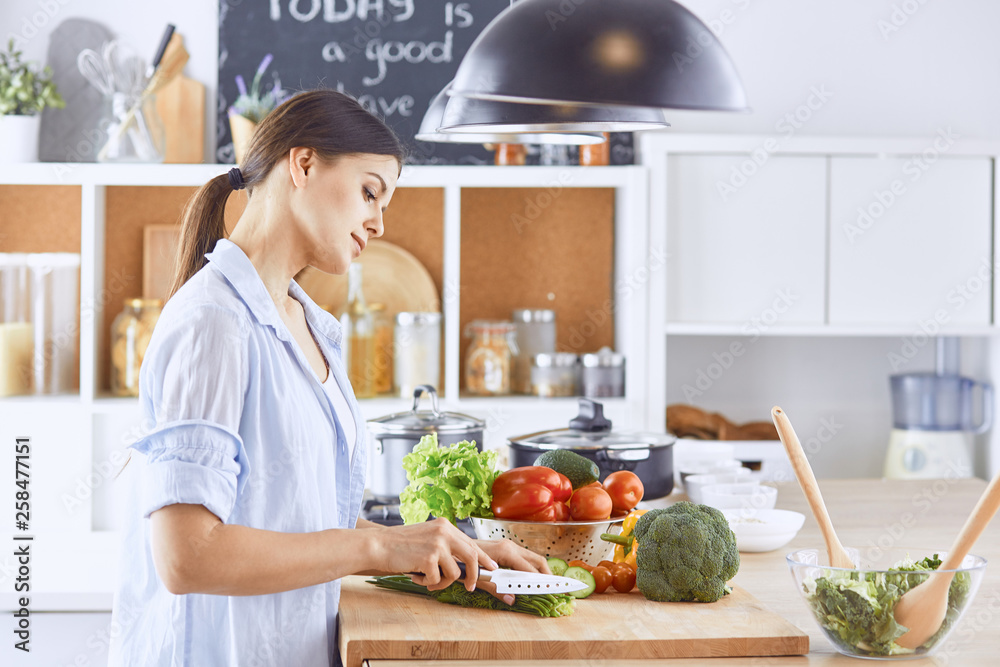 A young woman prepares food in the kitchen. Healthy food - vege A young woman prepares food in the kitchen. Healthy food - vege