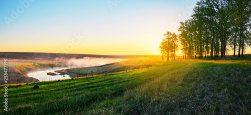 Foggy spring landscape with river and green hills
