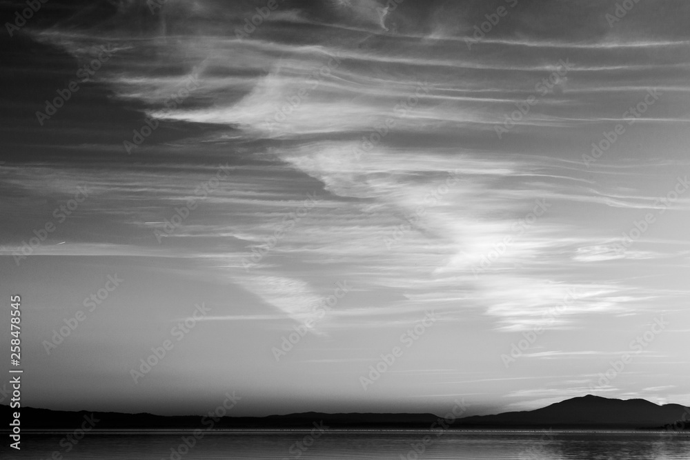 Beautiful view of Trasimeno lake (Umbria, Italy) at sunset, with cloud shapes on the sky Beautiful view of Trasimeno lake (Umbria, Italy) at sunset, with cloud shapes on the sky